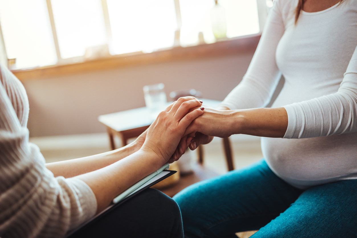 Pregnant woman on home counselling meeting. You're not in this alone. Depressed pregnant woman consultation with psychologist. Psychiatrist holding hands patient,such as making a fresh start and loving yourself