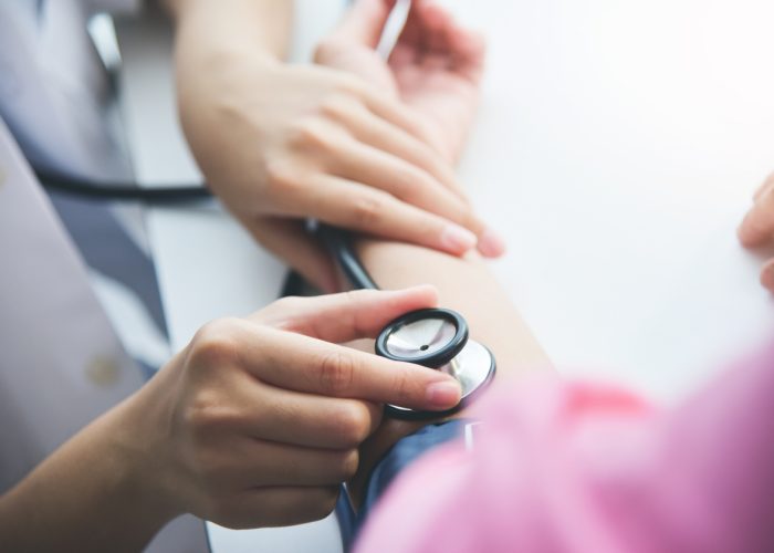 Asian Female doctor measuring blood pressure of a senior woman patient. Stethoscope. Health care.